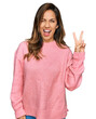 © Krakenimages.com - Young hispanic woman wearing casual clothes smiling with happy face winking at the camera doing victory sign with fingers. number two.