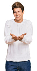 Wall Mural - Handsome caucasian man wearing casual white sweater smiling with hands palms together receiving or giving gesture. hold and protection