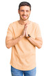© Krakenimages.com - Handsome young man with bear wearing casual yellow tshirt praying with hands together asking for forgiveness smiling confident.