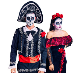 Poster - young couple wearing mexican day of the dead costume over background relaxed with serious expression