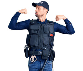 Canvas Print - Young handsome man wearing police uniform showing arms muscles smiling proud. fitness concept.