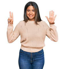 Sticker - Young latin girl wearing wool winter sweater showing and pointing up with fingers number seven while smiling confident and happy.