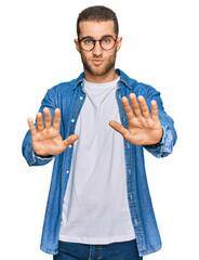 Poster - Young caucasian man wearing casual clothes moving away hands palms showing refusal and denial with afraid and disgusting expression. stop and forbidden.