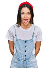 Poster - Young hispanic girl wearing casual clothes sticking tongue out happy with funny expression. emotion concept.