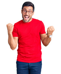 Canvas Print - Young hispanic man wearing casual clothes and glasses screaming proud, celebrating victory and success very excited with raised arms