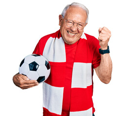 Sticker - Senior man with grey hair football hooligan holding ball very happy and excited doing winner gesture with arms raised, smiling and screaming for success. celebration concept.