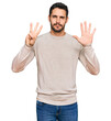 © Krakenimages.com - Young hispanic man wearing casual clothes showing and pointing up with fingers number eight while smiling confident and happy.