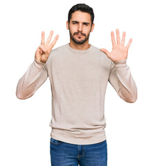 Wall Mural - Young hispanic man wearing casual clothes showing and pointing up with fingers number eight while smiling confident and happy.