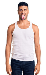 Sticker - Young hispanic man wearing casual clothes sticking tongue out happy with funny expression. emotion concept.