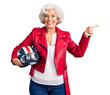 © Krakenimages.com - Senior grey-haired woman holding motorcycle helmet smiling happy pointing with hand and finger to the side