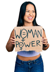 Wall Mural - Beautiful hispanic woman holding woman power banner smiling and laughing hard out loud because funny crazy joke.