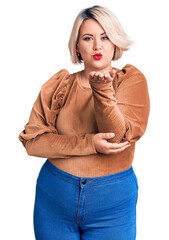 Wall Mural - Young blonde plus size woman wearing casual sweater looking at the camera blowing a kiss with hand on air being lovely and sexy. love expression.