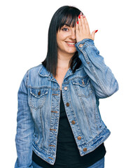 Canvas Print - Young hispanic woman wearing casual clothes covering one eye with hand, confident smile on face and surprise emotion.