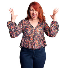 Wall Mural - Young beautiful redhead woman wearing casual t-shirt celebrating mad and crazy for success with arms raised and closed eyes screaming excited. winner concept