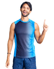 Poster - Handsome hispanic man wearing sportswear showing and pointing up with finger number one while smiling confident and happy.