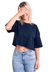 Sticker - Young beautiful blonde woman wearing casual t-shirt smiling and laughing with hand on face covering eyes for surprise. blind concept.