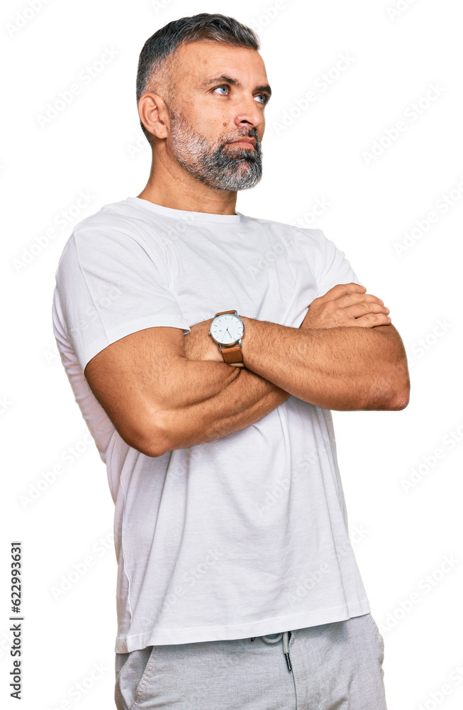 Middle age handsome man wearing casual white tshirt looking to the side with arms crossed convinced and confident