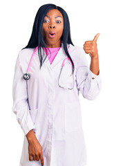 Canvas Print - Young african american woman wearing doctor stethoscope surprised pointing with hand finger to the side, open mouth amazed expression.