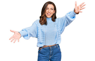 Canvas Print - Young brunette woman wearing casual winter sweater looking at the camera smiling with open arms for hug. cheerful expression embracing happiness.