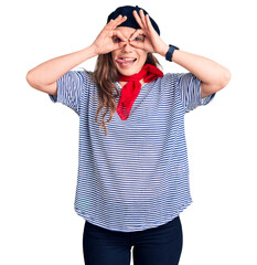 Poster - Young beautiful blonde woman wearing french beret and striped t-shirt doing ok gesture like binoculars sticking tongue out, eyes looking through fingers. crazy expression.