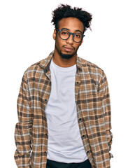 Wall Mural - Young african american man with beard wearing casual clothes and glasses looking sleepy and tired, exhausted for fatigue and hangover, lazy eyes in the morning.