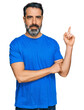 © Krakenimages.com - Middle aged man with beard wearing casual blue t shirt with a big smile on face, pointing with hand and finger to the side looking at the camera.