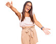 Young hispanic woman wearing casual clothes and glasses looking at the camera smiling with open arms for hug. cheerful expression embracing happiness.