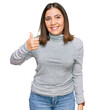 © Krakenimages.com - Young beautiful woman wearing casual turtleneck sweater doing happy thumbs up gesture with hand. approving expression looking at the camera showing success.