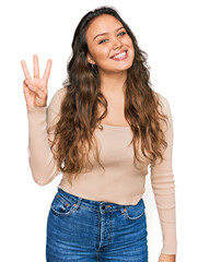 Canvas Print - Young hispanic girl wearing casual clothes showing and pointing up with fingers number three while smiling confident and happy.