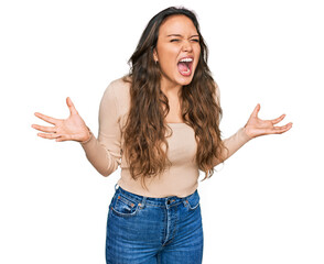 Sticker - Young hispanic girl wearing casual clothes crazy and mad shouting and yelling with aggressive expression and arms raised. frustration concept.