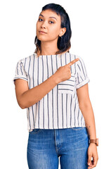 Wall Mural - Young woman wearing casual clothes pointing with hand finger to the side showing advertisement, serious and calm face