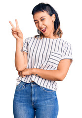 Sticker - Young woman wearing casual clothes smiling with happy face winking at the camera doing victory sign with fingers. number two.