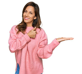 Poster - Young hispanic woman wearing casual clothes showing palm hand and doing ok gesture with thumbs up, smiling happy and cheerful