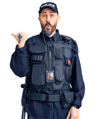 Poster - Young handsome man wearing police uniform surprised pointing with hand finger to the side, open mouth amazed expression.