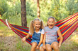 © Inna Vlasova - Kids relax in colorful rainbow hammock. Hot day garden outdoor fun. Afternoon nap during summer vacation. Children relaxing.