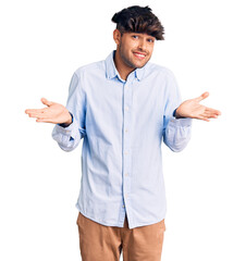 Wall Mural - Young hispanic man wearing casual shirt clueless and confused expression with arms and hands raised. doubt concept.