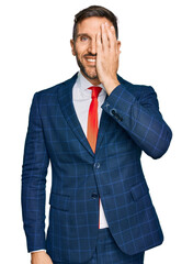 Sticker - Handsome man with beard wearing business suit and tie covering one eye with hand, confident smile on face and surprise emotion.