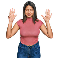 Poster - Young hispanic girl wearing casual t shirt showing and pointing up with fingers number nine while smiling confident and happy.