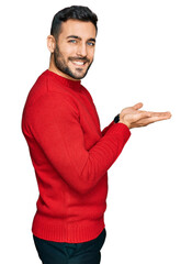 Poster - Young hispanic man wearing casual clothes pointing aside with hands open palms showing copy space, presenting advertisement smiling excited happy