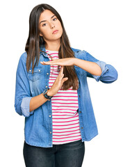 Poster - Young brunette woman wearing casual clothes doing time out gesture with hands, frustrated and serious face