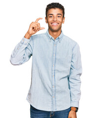 Sticker - Young handsome african american man wearing casual clothes smiling and confident gesturing with hand doing small size sign with fingers looking and the camera. measure concept.