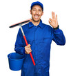 © Krakenimages.com - Bald man with beard wearing glass cleaner uniform and squeegee doing ok sign with fingers, smiling friendly gesturing excellent symbol
