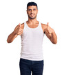 © Krakenimages.com - Young hispanic man wearing casual clothes success sign doing positive gesture with hand, thumbs up smiling and happy. cheerful expression and winner gesture.