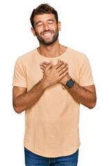 Poster - Handsome young man with beard wearing casual tshirt smiling with hands on chest with closed eyes and grateful gesture on face. health concept.