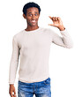 © Krakenimages.com - African handsome man wearing casual winter sweater smiling and confident gesturing with hand doing small size sign with fingers looking and the camera. measure concept.