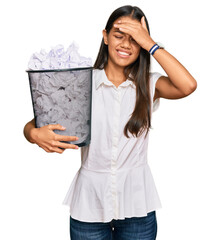 Poster - Beautiful hispanic woman holding paper bin full of crumpled papers stressed and frustrated with hand on head, surprised and angry face