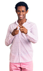 Canvas Print - African handsome man wearing casual pink shirt pointing fingers to camera with happy and funny face. good energy and vibes.