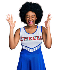 Sticker - Young african american woman wearing cheerleader uniform celebrating mad and crazy for success with arms raised and closed eyes screaming excited. winner concept