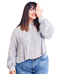 Canvas Print - Young plus size woman wearing casual clothes covering one eye with hand, confident smile on face and surprise emotion.