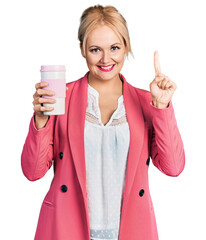 Canvas Print - Young blonde woman wearing business clothes and drinking coffee smiling with an idea or question pointing finger with happy face, number one